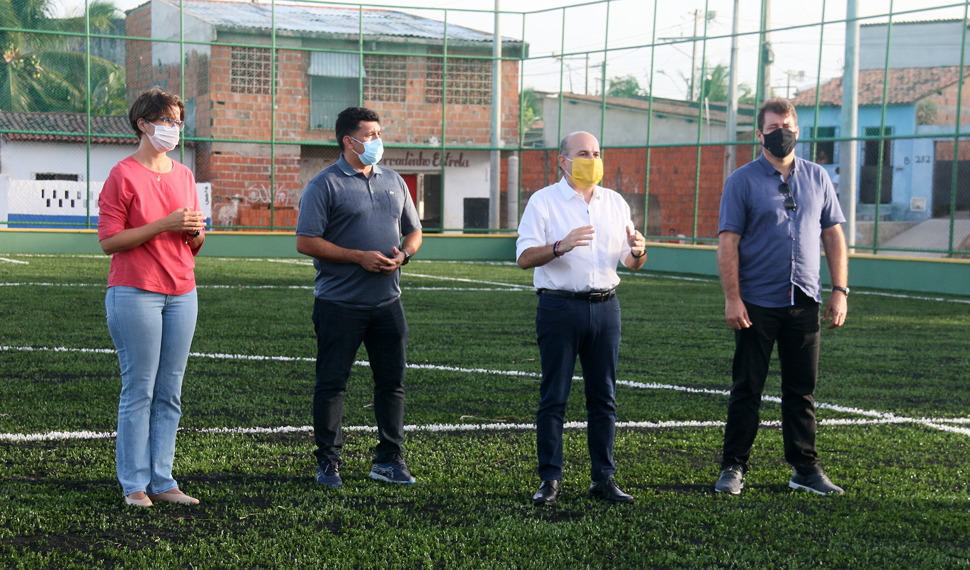 prefeito, secretária Manuela Nogueira e dois secretários em pé de máscara em campo da Areninha